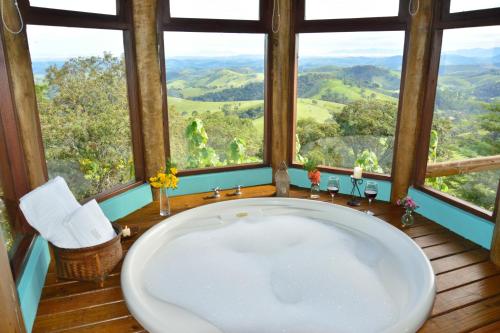 a bathroom with a large tub in front of a window at Pousada Quinta da Serra in Cunha