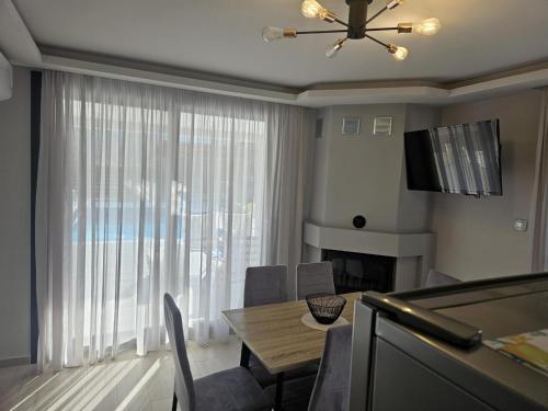 a living room with a dining room table and a large window at OLYMPUS Paradise 2 in Skotína