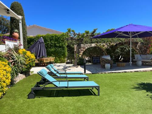 four lounge chairs and an umbrella on the grass at HOTEL LA QUIETUDE in Les Issambres