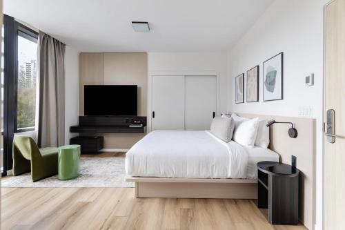 a white bedroom with a bed and a flat screen tv at Smithe House in Vancouver