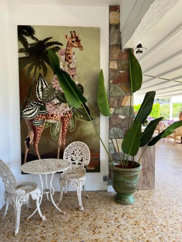 a room with a table and chairs and a painting at HOTEL LA QUIETUDE in Les Issambres