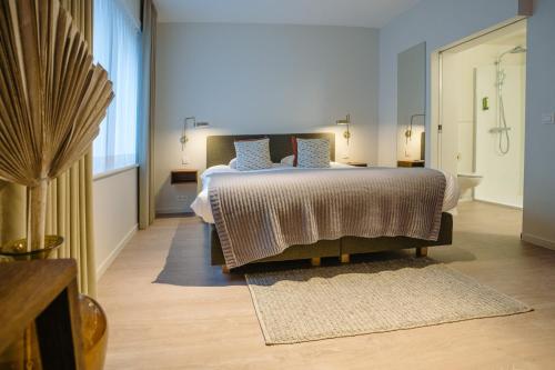 a bedroom with a large bed and a bathroom at Hotel du Bassin in Ostend