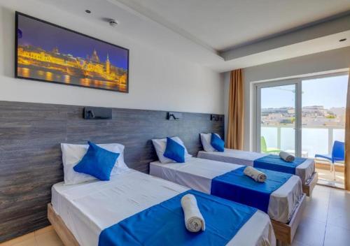 a hotel room with three beds and a large window at Bayside A Apartments in St Julian's