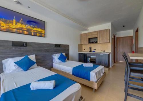 a hotel room with two beds and a kitchen at Bayside A Apartments in St Julian's