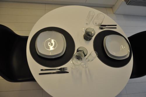 a white table with black plates and glasses on it at Duomo intero appartamento in Milan