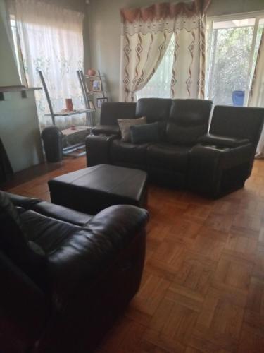 a living room with a leather couch and a table at Town Charm Guesthouse in Germiston