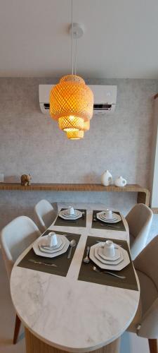 a dining room table with chairs and a chandelier at Parque do Cais - Flats Premium no Recife por Yolo in Recife