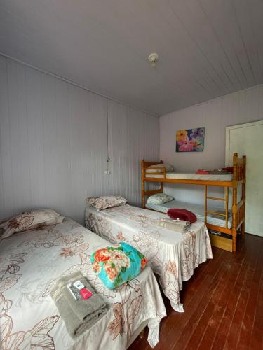 a room with two beds and a table in it at Hotel Pousada e Parada Colonial in Capitão Leônidas Marques