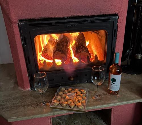 a fireplace with a tray of food and two wine glasses at Sunshine villa Dzhigurovo in Sandanski