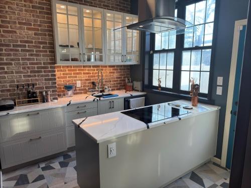 a kitchen with white cabinets and a brick wall at NEW Modern Private Entrance 2 BD Apt Minutes to NYC in Jersey City