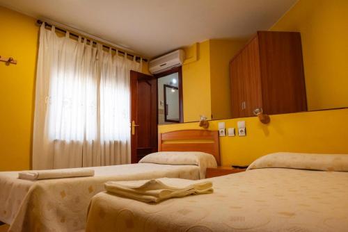 a hotel room with two beds with yellow walls at Pensión Discoves in Pinseque