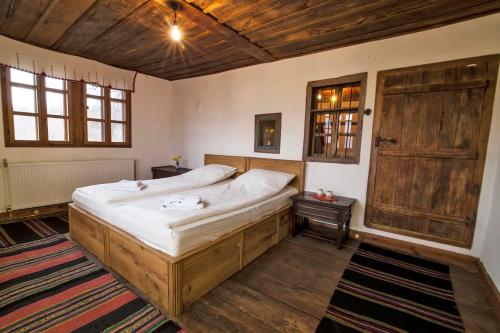 a bedroom with a large bed and a wooden door at Authentic House with Stunning Mountain View - Karashka in Apriltsi