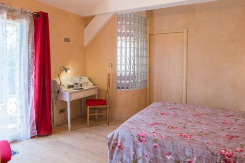 a bedroom with a bed and a desk and a window at Homgaïa chambres d'hôtes in Clisson