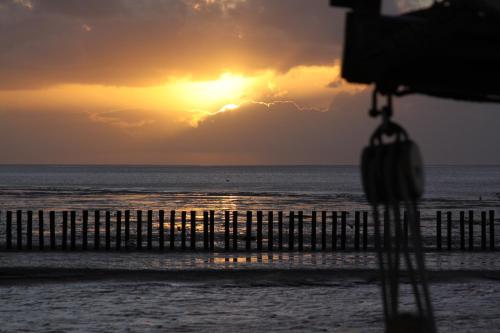 een zonsondergang boven het strand met een hek bij Studio 43 in Hollum