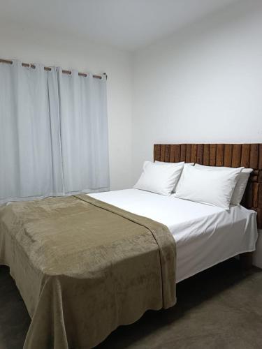 a bedroom with a large bed with white sheets and pillows at Chales Villa assu in Amontada
