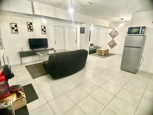 a living room with a black couch and a refrigerator at BeautifulLoft près Disneyland/Astérix/Aéroport CDG in Claye-Souilly
