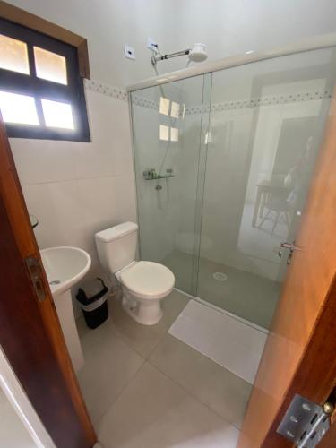 a bathroom with a toilet and a glass shower at Pousada Kembali Maresias in Maresias