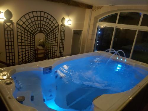 - une grande baignoire bleue dans une chambre avec fenêtre dans l'établissement La Ferme du BoisDieu, à Avallon