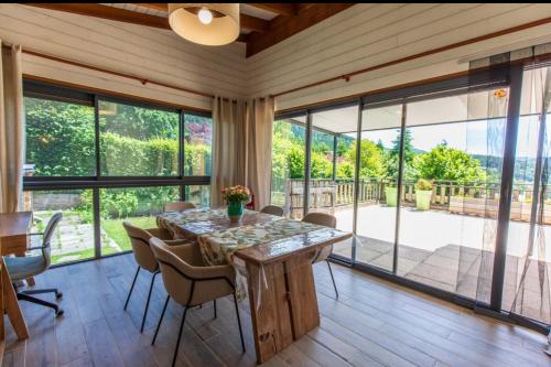 - une salle à manger avec une table, des chaises et des fenêtres en verre dans l'établissement Les Roses du Vercors Appartement, à Villard-de-Lans