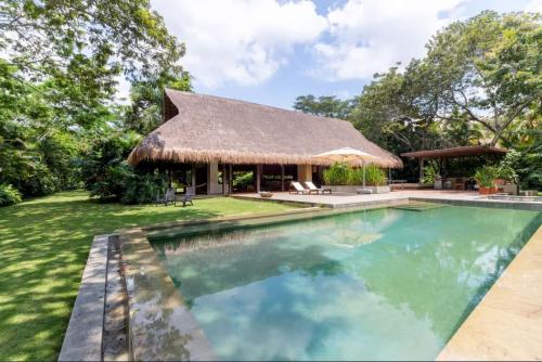 a house with a swimming pool and a thatch roof at Astonishing 5BR Villa at Mesa de Yeguas in Anapoima