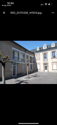 une photo d'un bâtiment avec un arbre devant lui dans l'établissement Petit Studio Gare SNCF, à Tarbes
