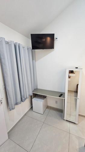 a room with a desk and a television and curtains at Pousada Bahamas Sc in Penha