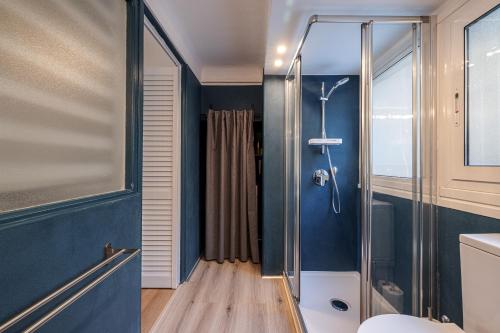 La salle de bains est pourvue d'une douche aux murs bleus. dans l'établissement ASTORIA - Magnifique duplex lumineux à 100m des plages, à Menton