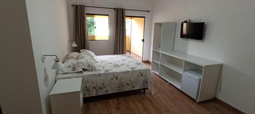 a bedroom with a bed and a dresser and a television at Pousada Alejandro in Cunha