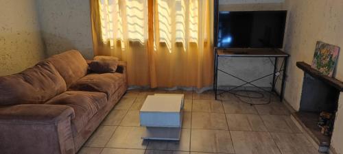 a living room with a couch and a flat screen tv at Cabaña el diquecito in La Calera