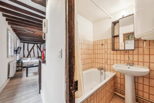 une salle de bain avec un lavabo et une baignoire dans l'établissement Cosy et charmant studio coeur du Marais, à Paris