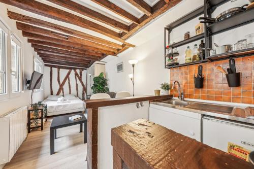 une cuisine avec des placards blancs et un mur en briques dans l'établissement Cosy et charmant studio coeur du Marais, à Paris