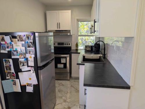 une cuisine avec un réfrigérateur noir et des armoires blanches dans l'établissement Luxury Studio located in downtown windsor for short term stay, à Windsor