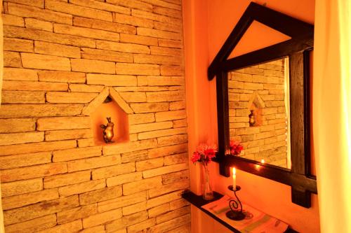 a bathroom with a mirror and a brick wall at Peace Eye Guest House in Pokhara