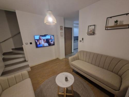 a living room with a couch and a tv on the wall at Vila Velebita in Vukovar