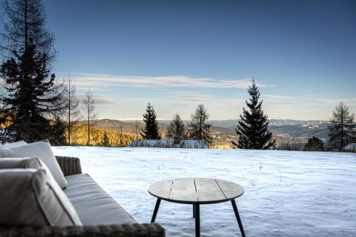 a living room with a couch and a table in the snow at dasHuber-Hochrindl in Hochrindl