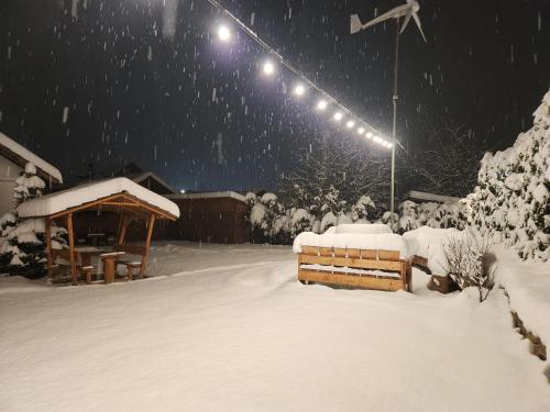 a snow covered yard with a bench and lights at Pensiunea Ioana in Sadova