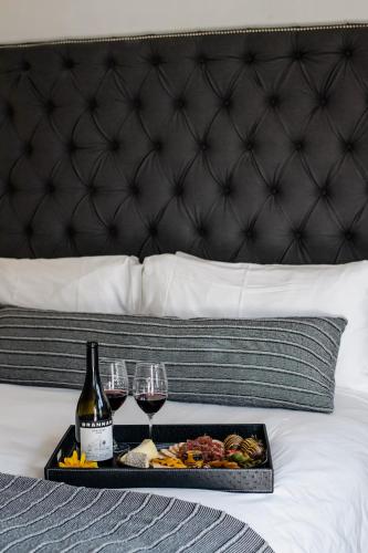a tray with wine glasses and food on a bed at Brannan Cottage Inn in Calistoga