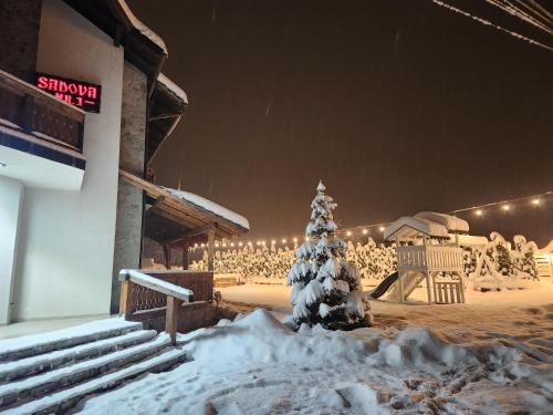 a snow covered christmas tree in front of a building at Pensiunea Ioana in Sadova