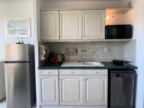 une cuisine avec des armoires blanches, un évier et un réfrigérateur dans l'établissement Résidence Héliopolis Bâtiment Ab - Studio 4 pers - Héliopolis Bât. AB MAE-3044, au Cap d'Agde