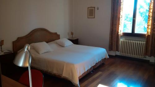 um quarto com uma cama, um candeeiro e uma janela em Villa dei Pini em Villorba