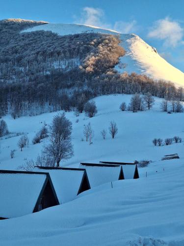 a snow covered hill with houses and a mountain at Kamp Kruščić - Laništa in Mojkovac