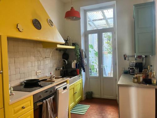 d'une cuisine avec des placards jaunes, un évier et une fenêtre. dans l'établissement Jardin à Marseille, à Marseille