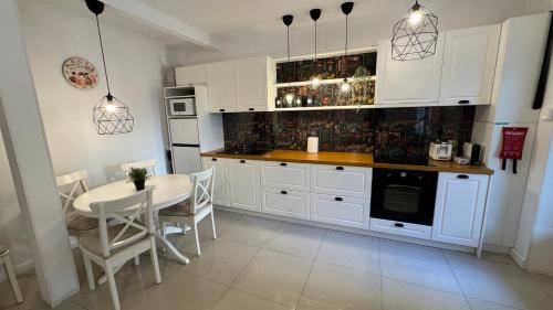 a kitchen with white cabinets and a table and chairs at BALI House Bucharest in Bucharest