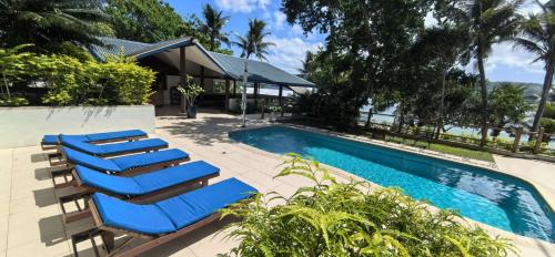 un gruppo di sedie a sdraio blu accanto a una piscina di Hideaway Island Resort a Port Vila