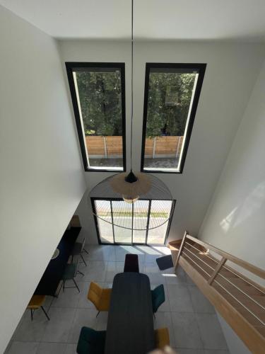 Cette chambre dispose de 3 fenêtres, d'une table et de chaises. dans l'établissement Maison 9p avec piscine et climatisation, à Lacanau