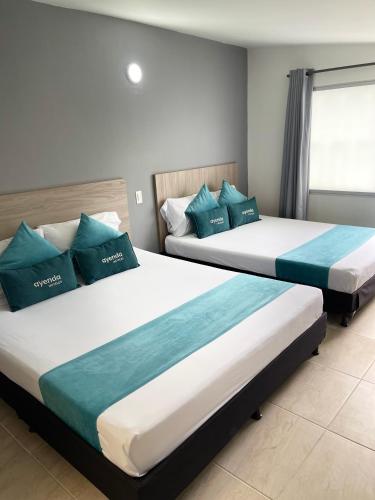 two beds in a hotel room with blue pillows at Hotel 12 Nights in Medellín