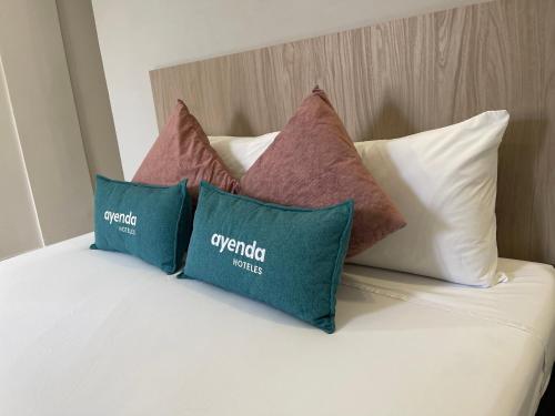 a bed with four pillows on top of it at Hotel 12 Nights in Medellín