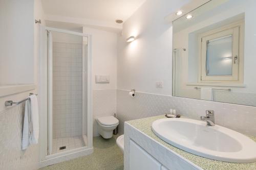 a white bathroom with a sink and a toilet at Maison du Lac in Stresa