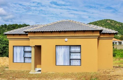 a small yellow house with two windows at Eden Groove Luxury self catering Guesthouse in Matsulu
