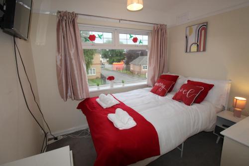 a bedroom with a bed with red pillows and a window at Sutton House in Sutton in Ashfield